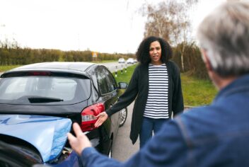 two people arguing next to a car accident on a highway