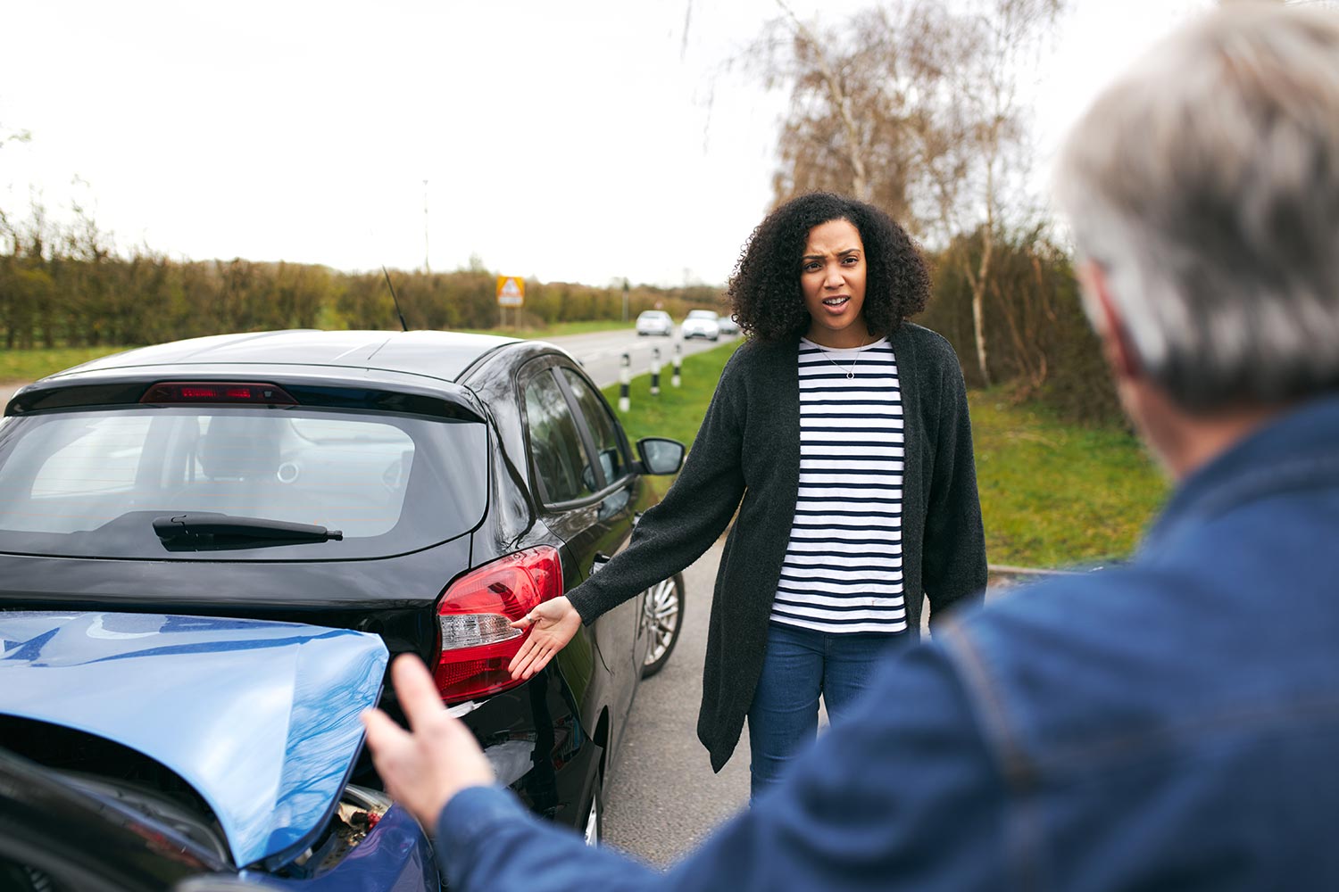two people arguing next to a car accident on a highway