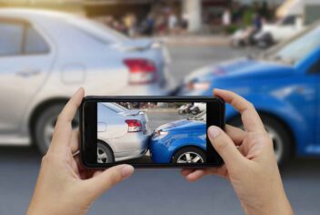 a person taking a cell phone photo of an auto accident