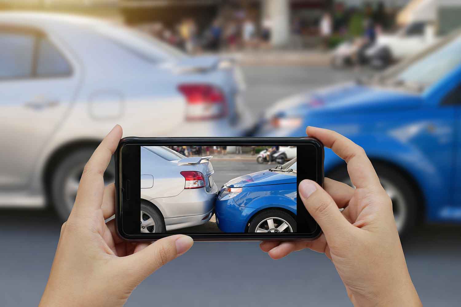 a person taking a cell phone photo of an auto accident