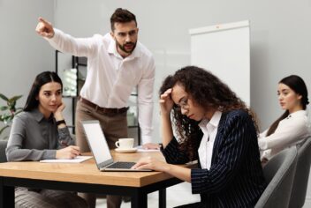 people in an office harassing a woman with a laptop