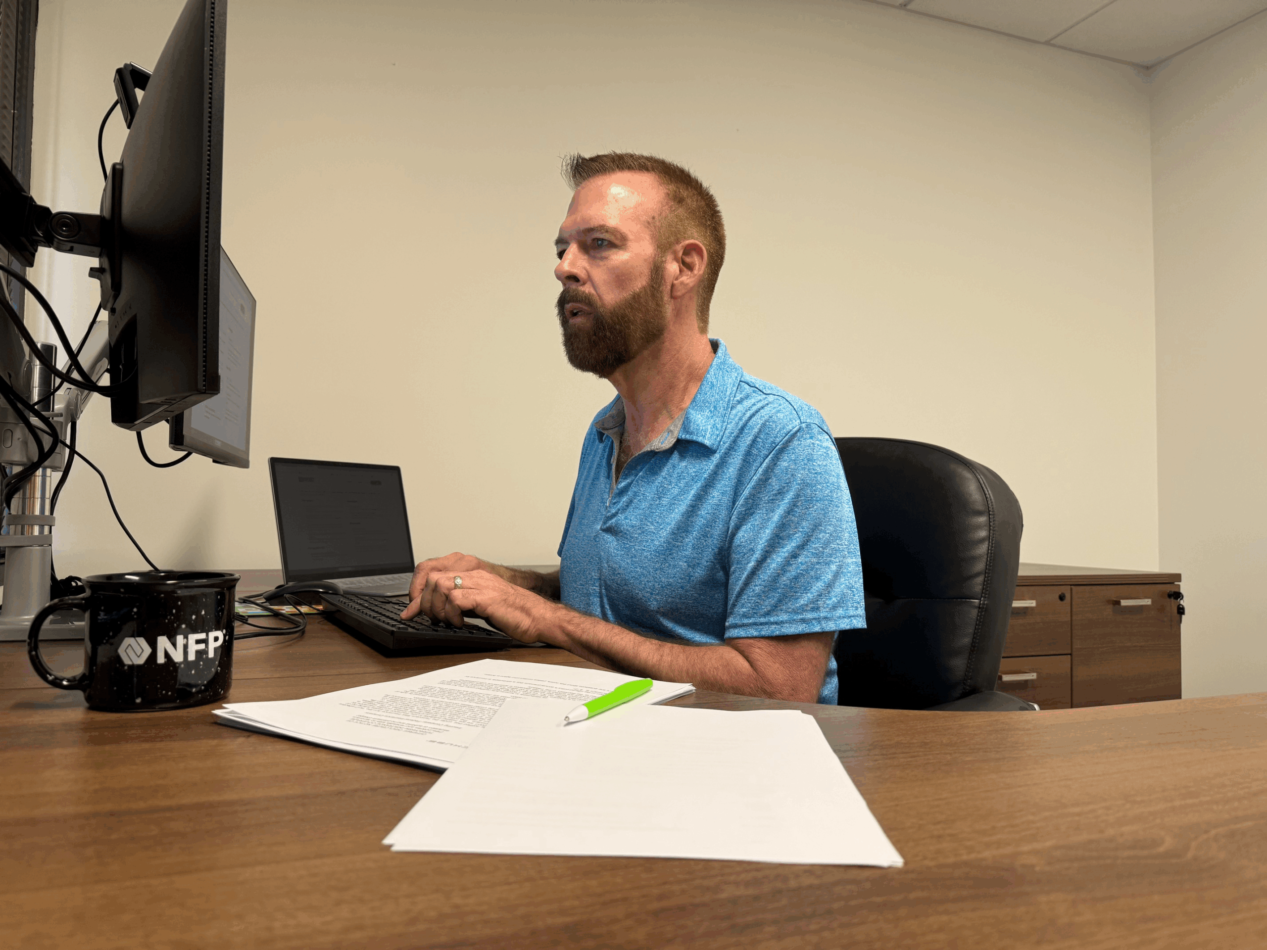 man sitting at desk looking at computer screen