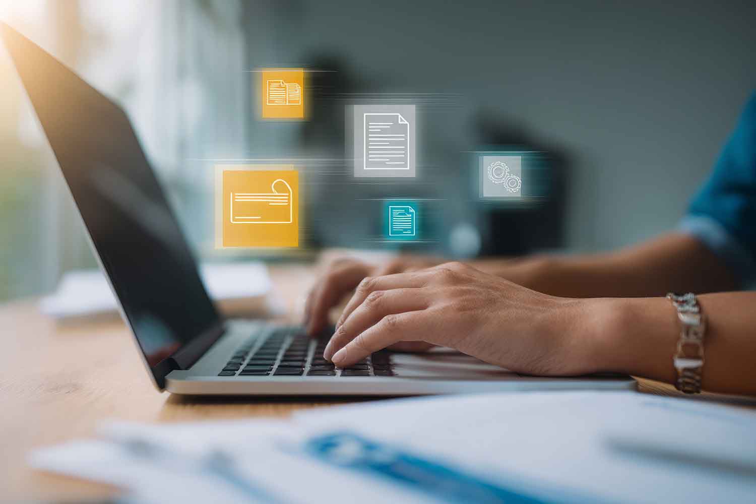 a person typing on a laptop with document icons floating above it