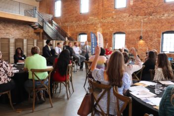 a panel of speakers in a large room with people sitting at tables