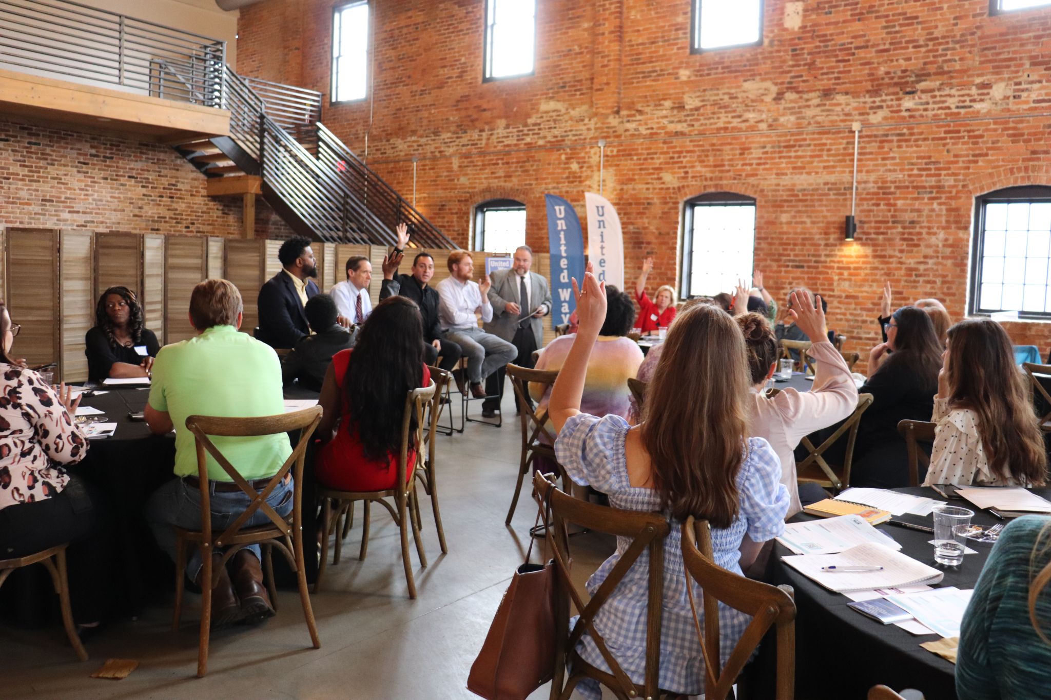 a panel of speakers in a large room with people sitting at tables