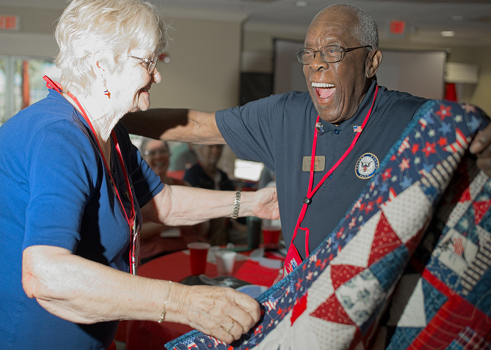 two people holding a quilt and hugging