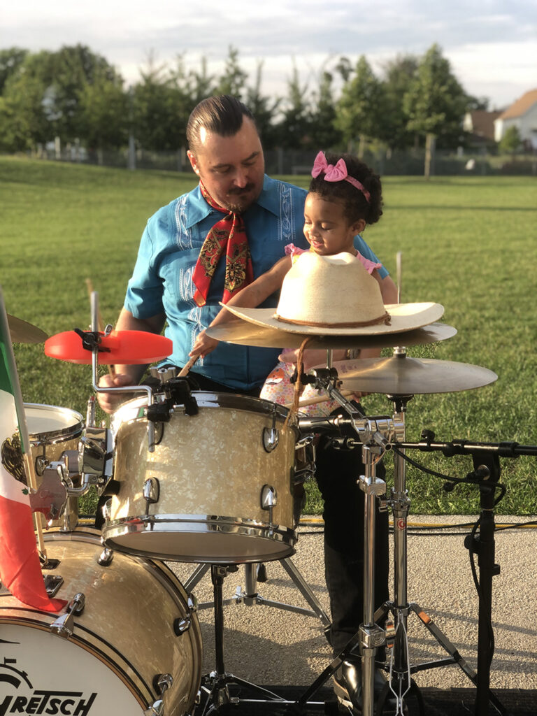 a man holding a young child while playing drums