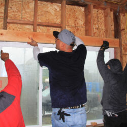 three people working on constructing a wall