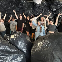 people holding up arms in a room filled with large plastic bags