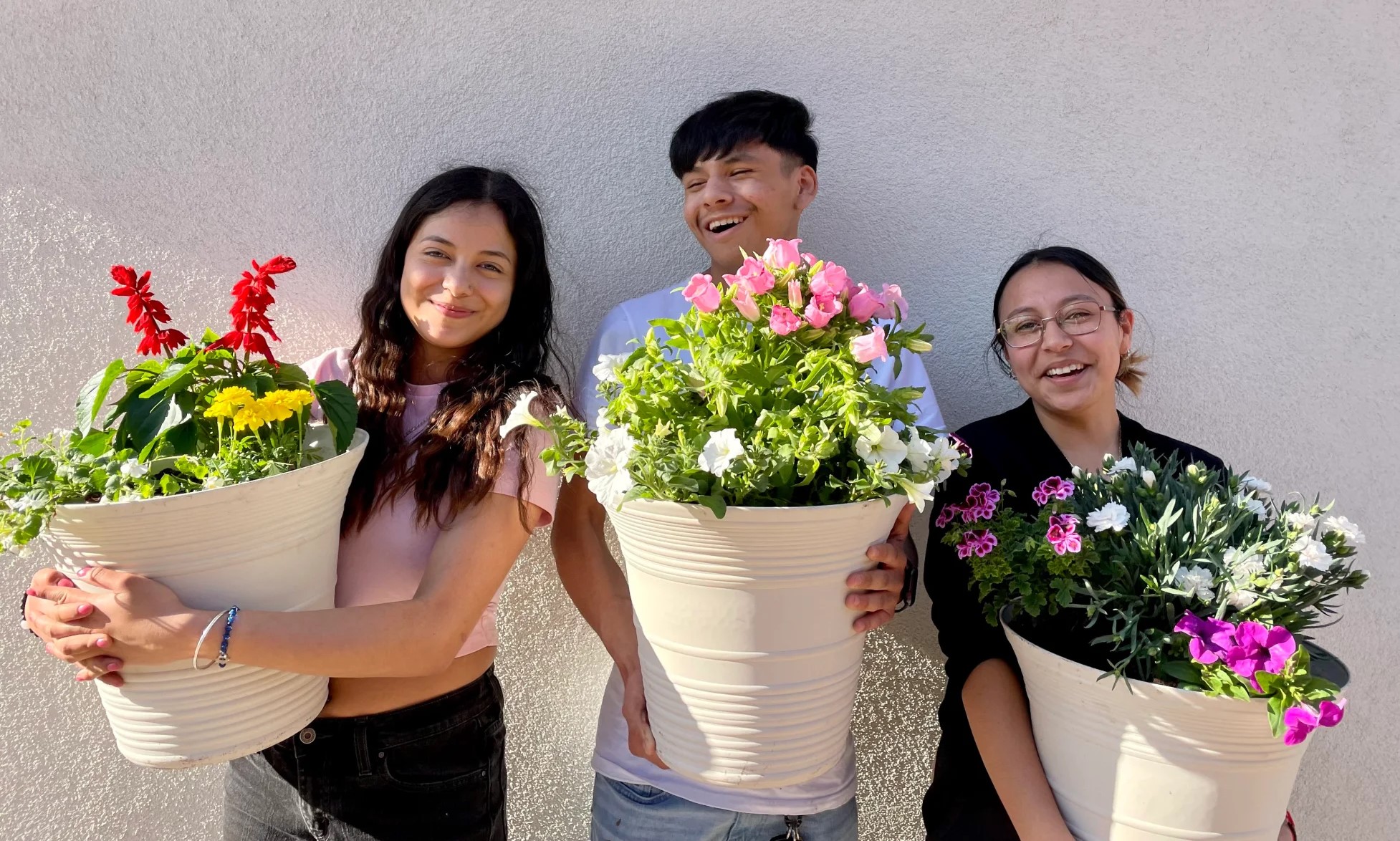 three people holding pots of flowers