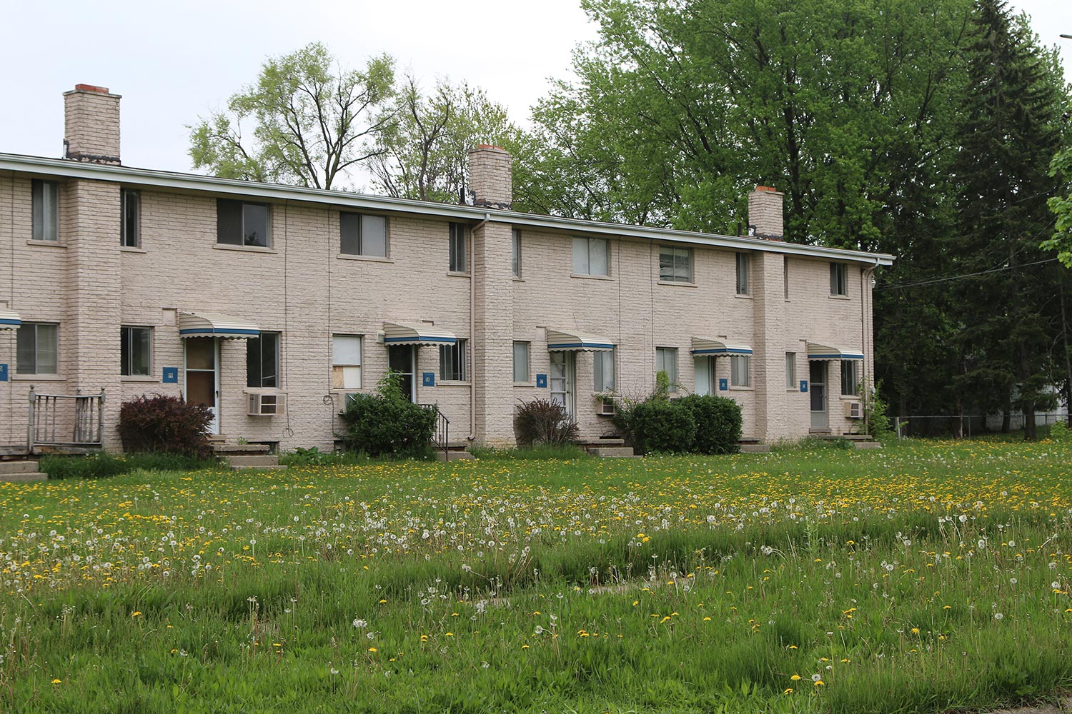 apartment building with weeds in yard