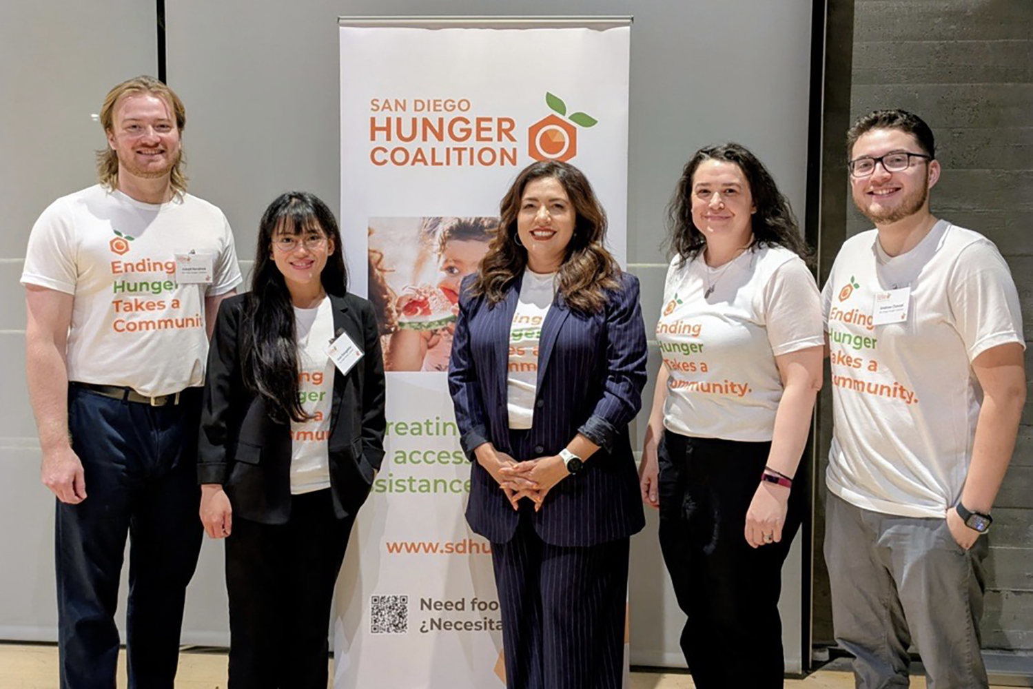 a group of people next to a sign for San Diego Hunger Coalition