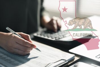 a person using a calculator and pen on notepad with California flag