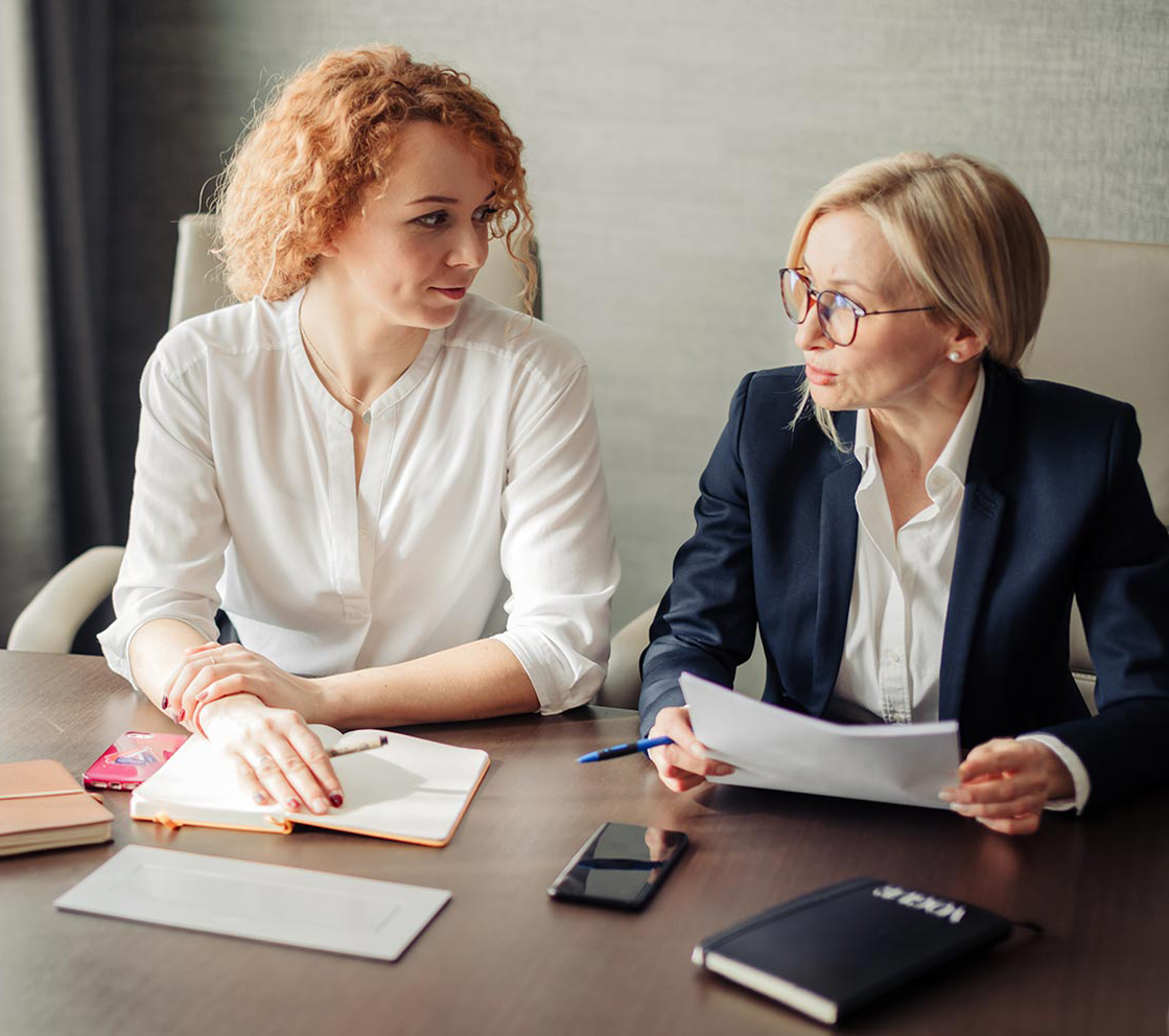 two women at a table with books and papers