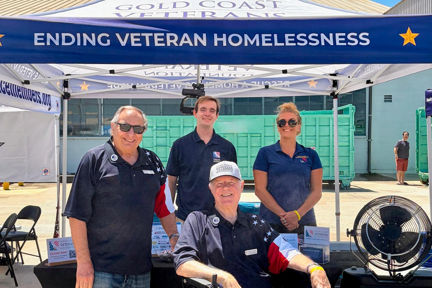 four people under a tent that reads: ending veteran homelessness