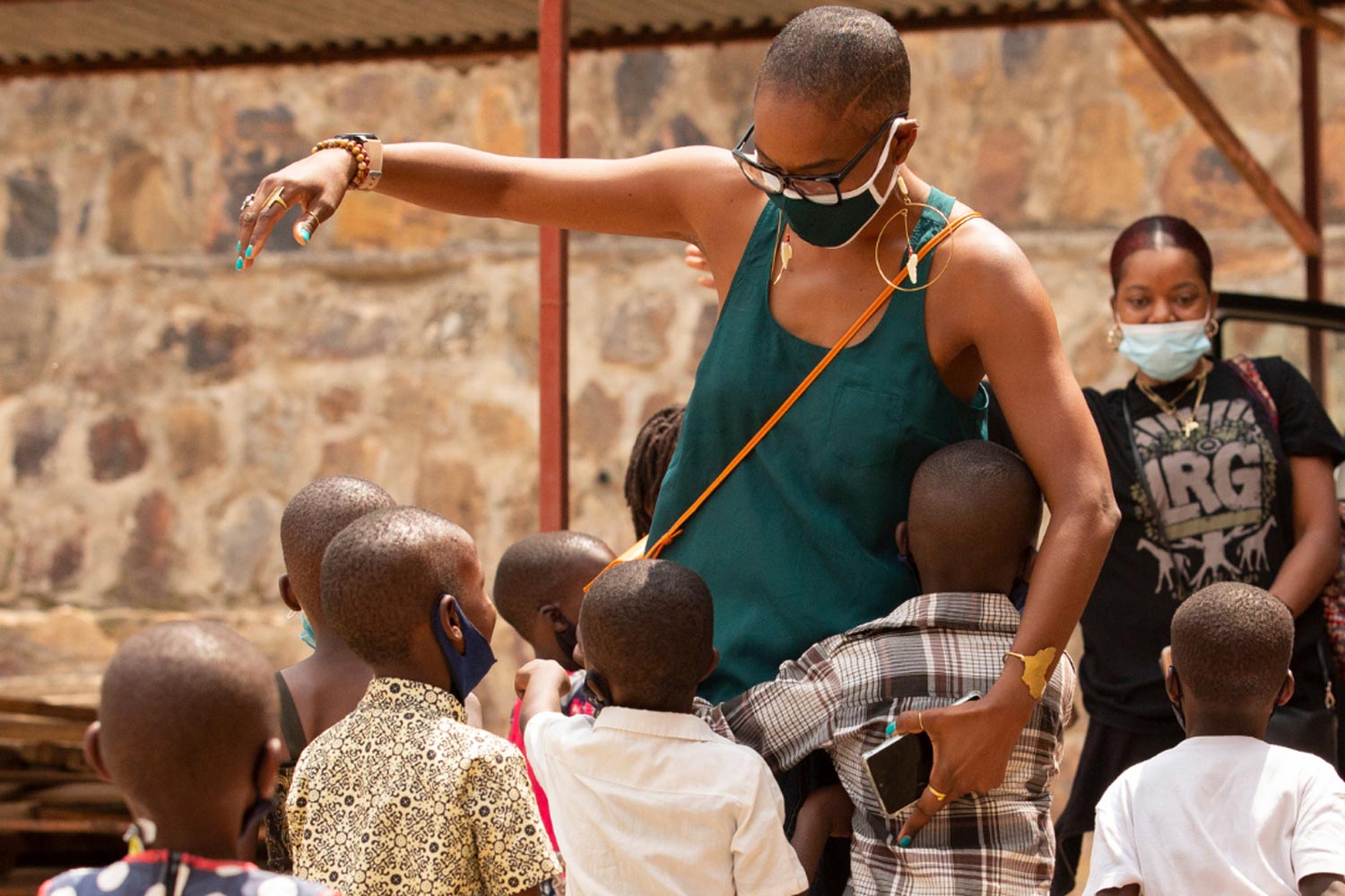 children hugging a woman wearing a mask