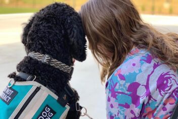 a woman and a service dog touching heads
