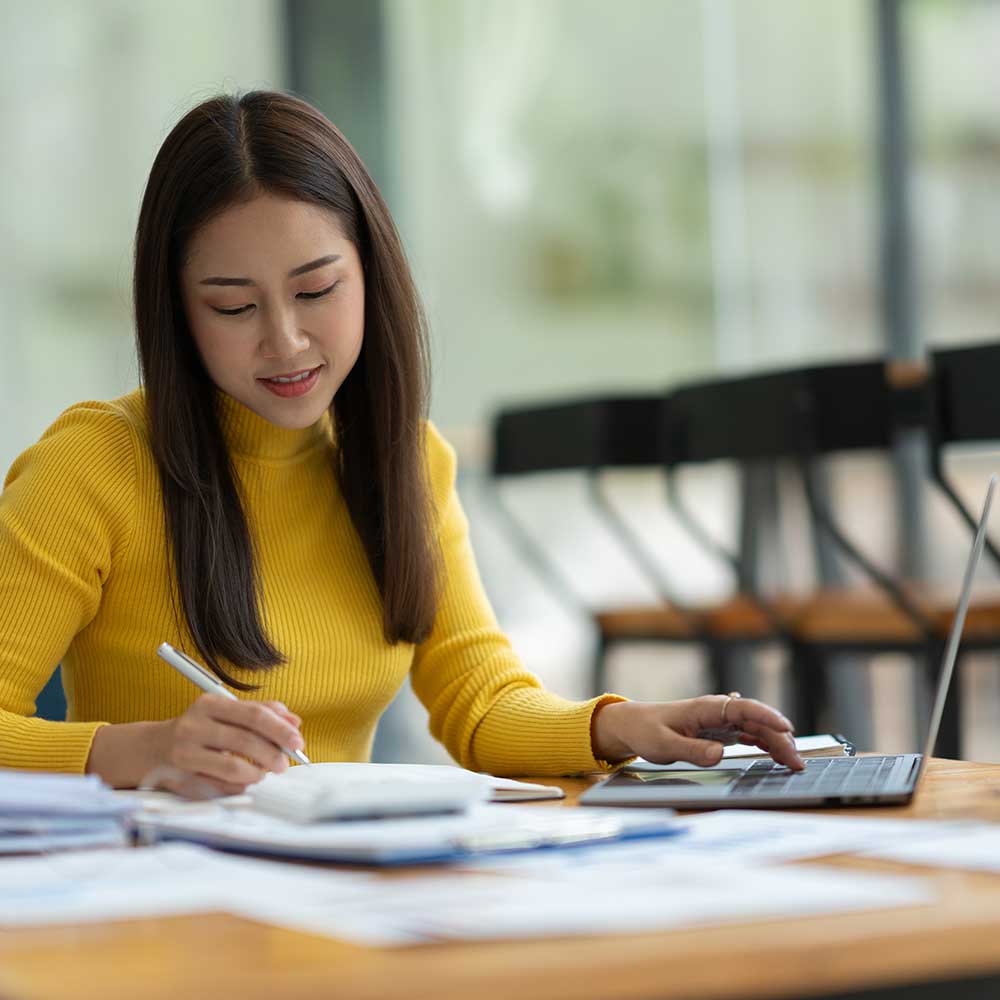 woman at a desk with a laptop and pen